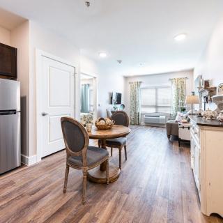 A modern apartment interior with a cozy living and dining area, featuring wood flooring and elegant furnishings.