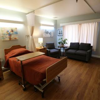 A comfortable and well-lit hospital room featuring a patient bed and seating area.