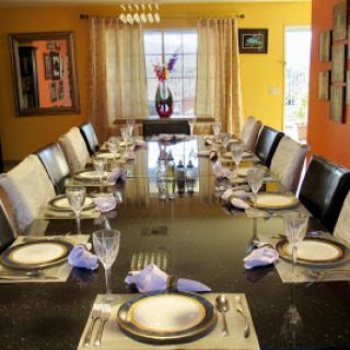 A beautifully set formal dining table in a modern interior with vibrant orange walls.