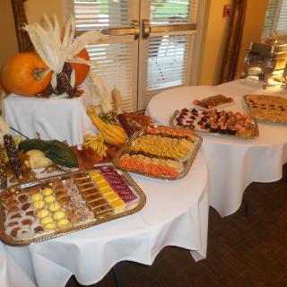 A buffet table elegantly arranged with a variety of desserts and fruits, accented by autumn-themed decorations.