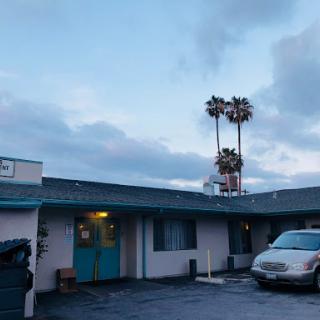 A serene evening at a quaint motel, highlighted by palm trees against the backdrop of a cloudy sky.