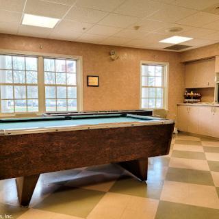 A cozy recreational room featuring a pool table and ample natural light.