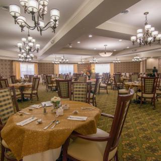 An elegant dining room with chandeliers and neatly arranged tables.
