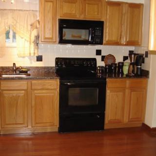 A modern kitchen with wooden cabinets, black appliances, and wood flooring.