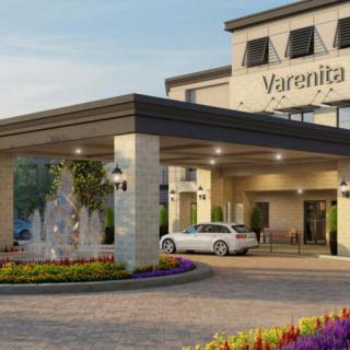 A modern building entrance with a fountain and parked car.