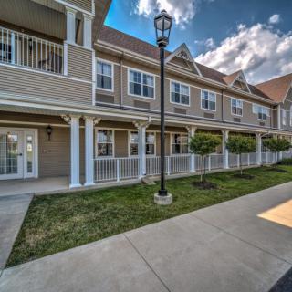 A view of a residential building with porches and landscaped surroundings.