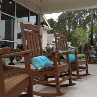 Wooden rocking chairs with blue cushions on a patio.