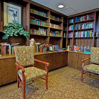 A cozy library corner with bookshelves filled with books and two upholstered chairs.
