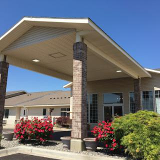 Welcoming entrance of a modern building surrounded by vibrant flowers on a sunny day.