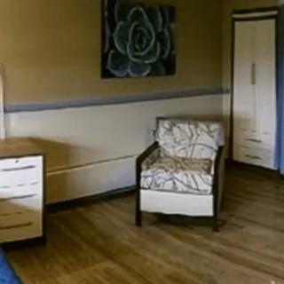 A simple room interior with a chair, cabinet, and wall artwork.