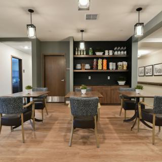 A modern dining area with stylish furniture, decorative shelving, and wood flooring.