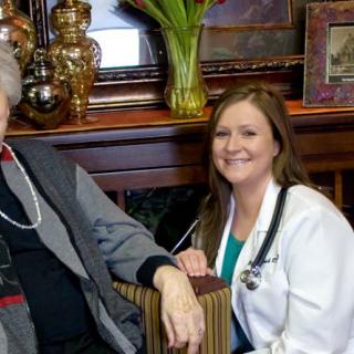 A healthcare professional smiling next to an elderly person indoors.