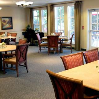 An elegantly arranged dining room with tables and chairs, featuring large windows for natural light.