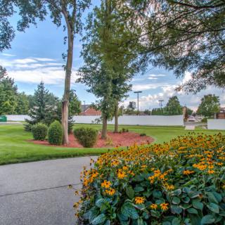 A scenic garden with vibrant flowers and lush green trees lining a pathway.