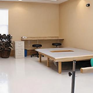 A spacious physical therapy room equipped with exercise tables and stools.