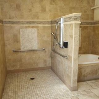 A spacious bathroom with a walk-in shower and bathtub, featuring tiled walls and accessibility grab bars.