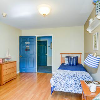 A cozy bedroom with a single bed, blue-themed decor, and wooden flooring.