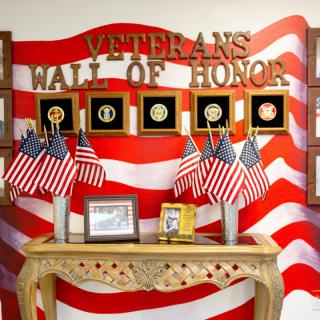 A patriotic display honoring veterans, featuring the 'Wall of Honor' with military emblems and American flags.