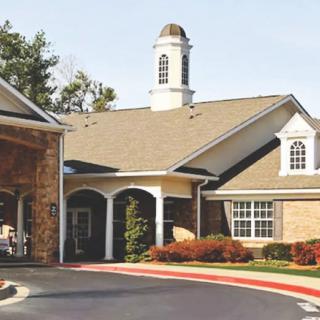 A residential building with a covered entrance and surrounding landscape.