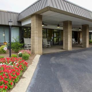 Covered entrance of a building with vibrant flower landscaping.