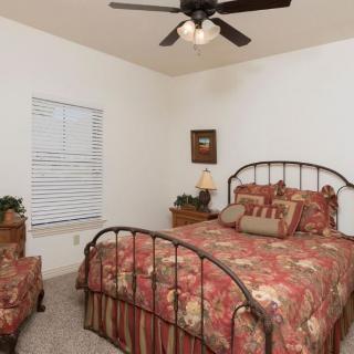 A cozy bedroom with a metal-framed bed, floral bedding, and a ceiling fan.