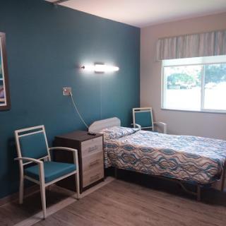 A cozy bedroom featuring a single bed, modern furniture, and blue accent walls.