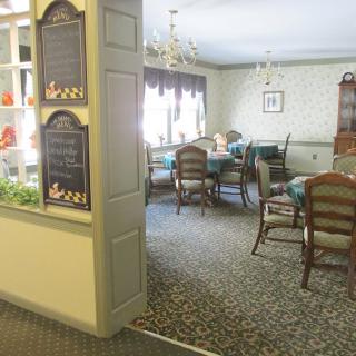 A cozy dining room with elegant chandeliers and neatly arranged tables and chairs.