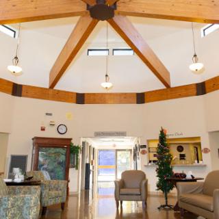 A spacious and well-lit lobby featuring a modern design with comfortable seating and a striking wooden ceiling.