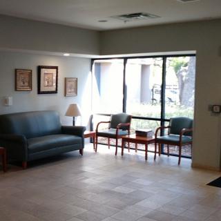 A well-lit waiting room with a sofa and several chairs arranged near a large window.