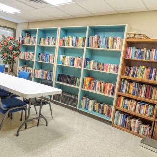 A cozy library reading room with bookshelves and a table with chairs.