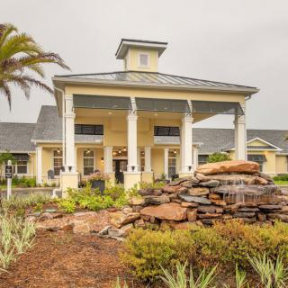 A grand entrance to a building with tall columns and a landscaped fountain.