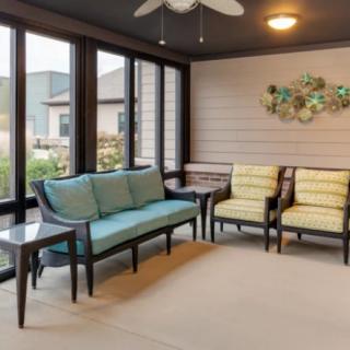 A cozy sunroom with comfortable seating and large windows.