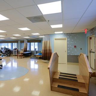 A spacious rehabilitation room equipped with exercise equipment and therapy stairs.