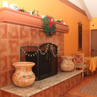A cozy indoor fireplace adorned with holiday decorations and vintage pots.