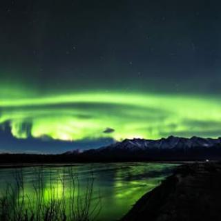 A stunning display of the Northern Lights illuminating the night sky over a tranquil landscape.