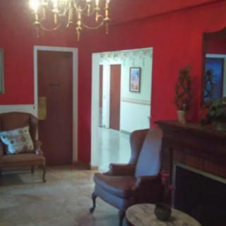 A cozy living room with vibrant red walls, featuring a chandelier and comfortable seating.