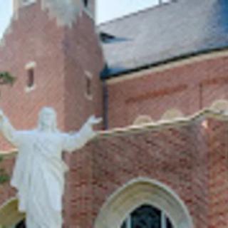 A church with a statue in front of a brick building.