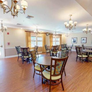 A well-lit dining area with several round tables and elegant chandeliers.