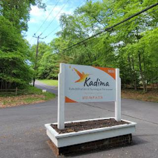 Welcome sign for Kadima, surrounded by lush greenery.