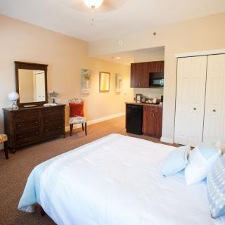 A cozy bedroom featuring a bed, dresser with a mirror, and a chair in neutral colors.