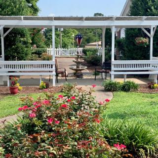 A beautifully landscaped garden with vibrant flowers, a pergola, and benches along a pathway.