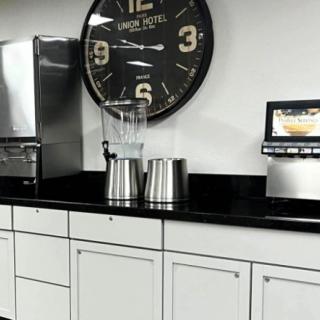 A modern kitchen setup with a large wall clock, blender, and other appliances on a sleek countertop.