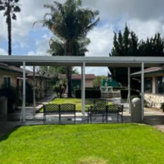 A well-maintained outdoor space featuring a green lawn and seating area under a canopy.