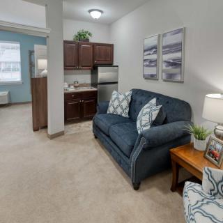 A cozy living area with a sofa and kitchenette in a modern apartment.