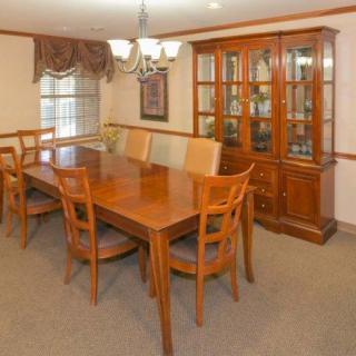 A formal dining room with a wooden table, chairs, and a glass cabinet.