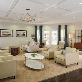 A spacious living room with elegant furnishings, featuring sofas, armchairs, a coffee table, and a chandelier.