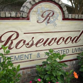 Sign for Rosewood Retirement and Assisted Living surrounded by plants.