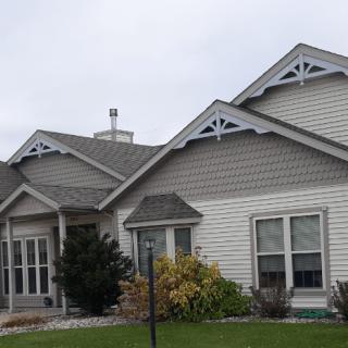A suburban house with a well-maintained yard and detailed exterior architecture.