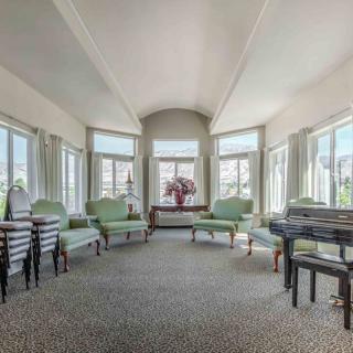 A spacious living room with large windows, allowing ample natural light to illuminate the space furnished with comfortable chairs and a central table.