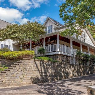 A charming residential house with a wraparound porch and stone landscaping.